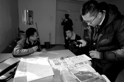 　执法人员收缴涉案地图，并将发放人员(右二)带回调查。市文化执法总队供图